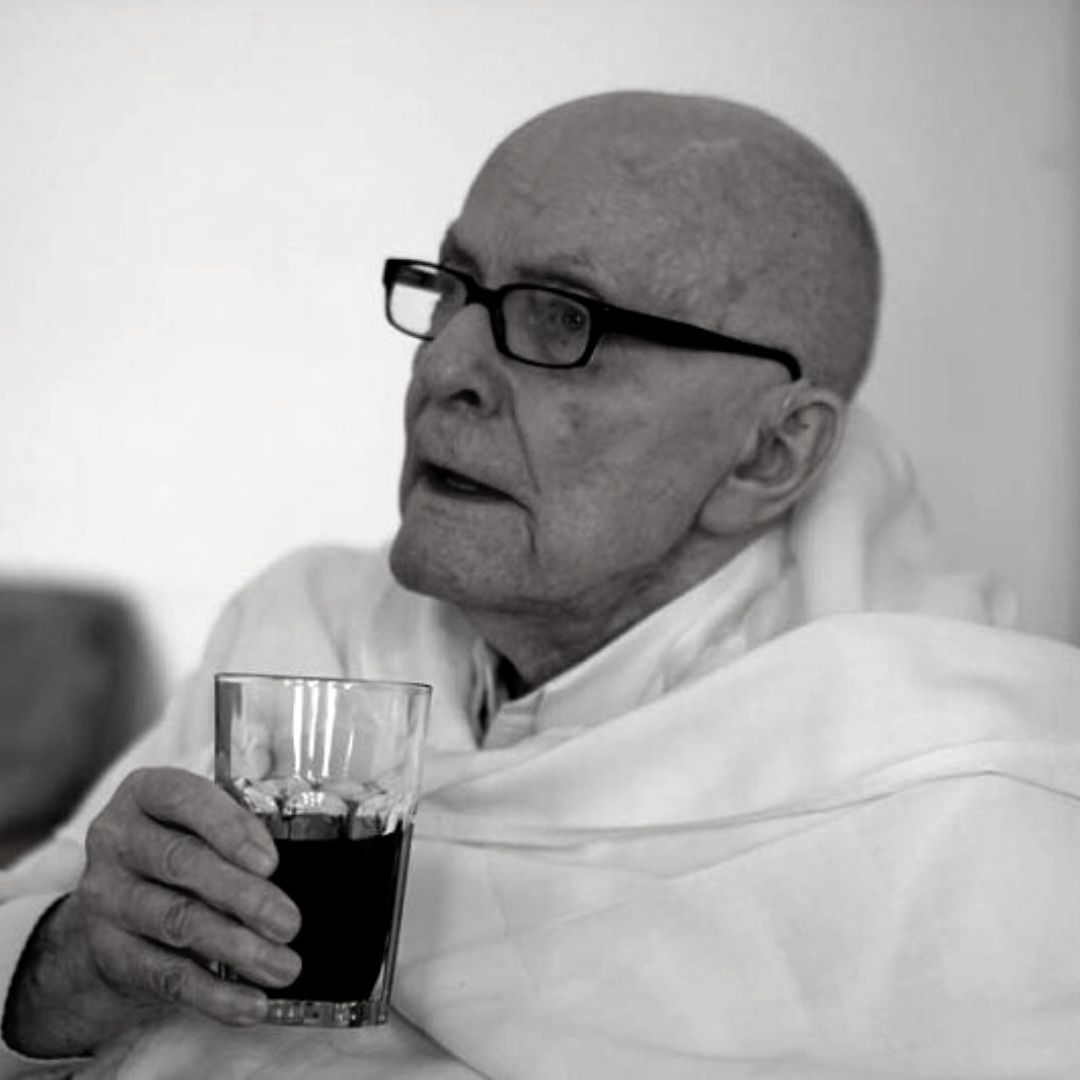 ojciec Joachim Badeni OP siedzi ze szklanką napoju