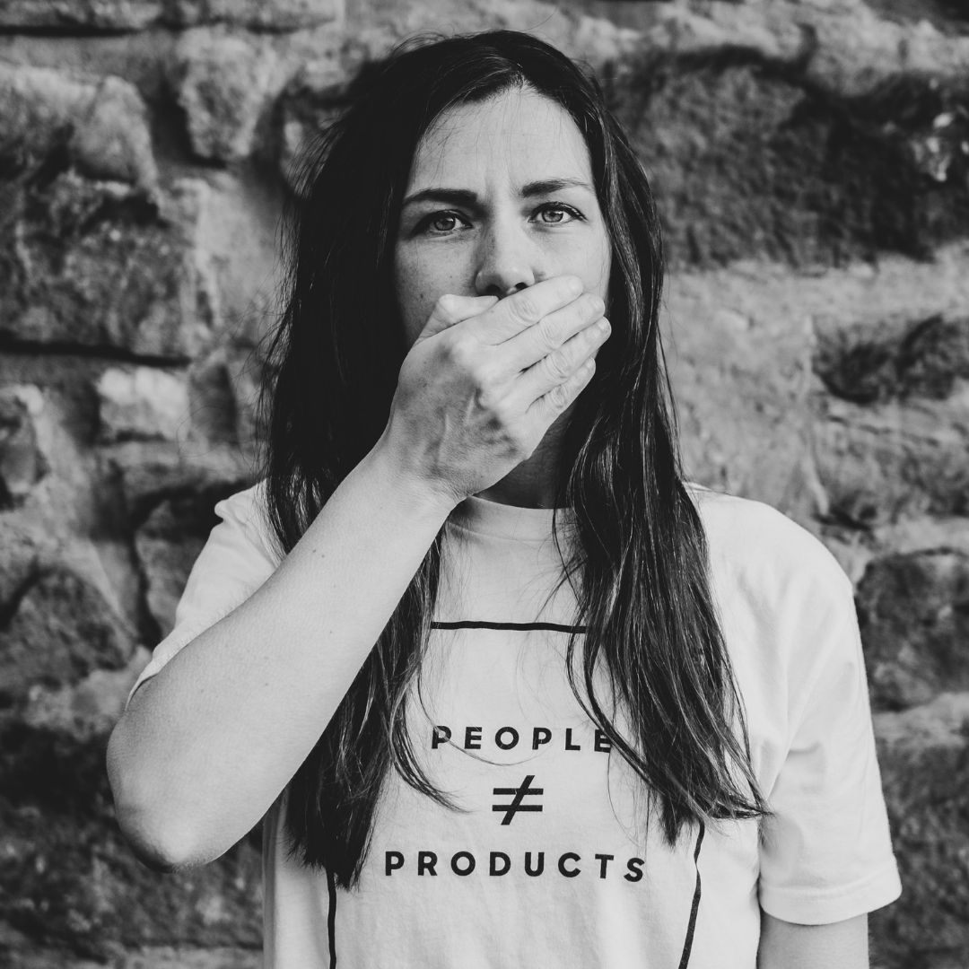 kobieta zasłaniająca sobie dłonią usta w koszulce z napisem people znak nierówności products co znaczy że ludzie nie są przedmiotami