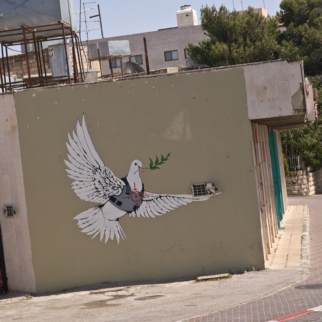 graffiti które namalował Banksy na West Bank Wall zatytułowane Armored Dove of Peace Opancerzony Gołąbek Pokoju