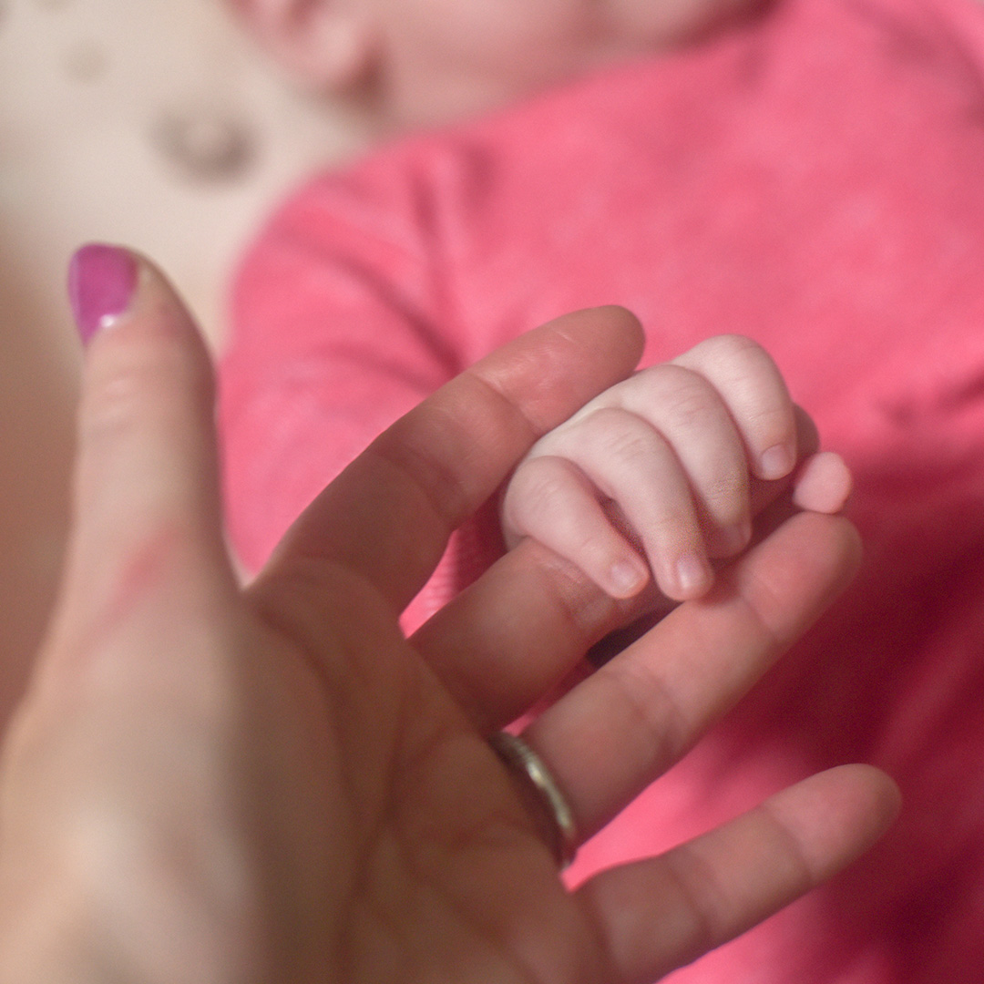 niemowlę chwytające rękę kobiety