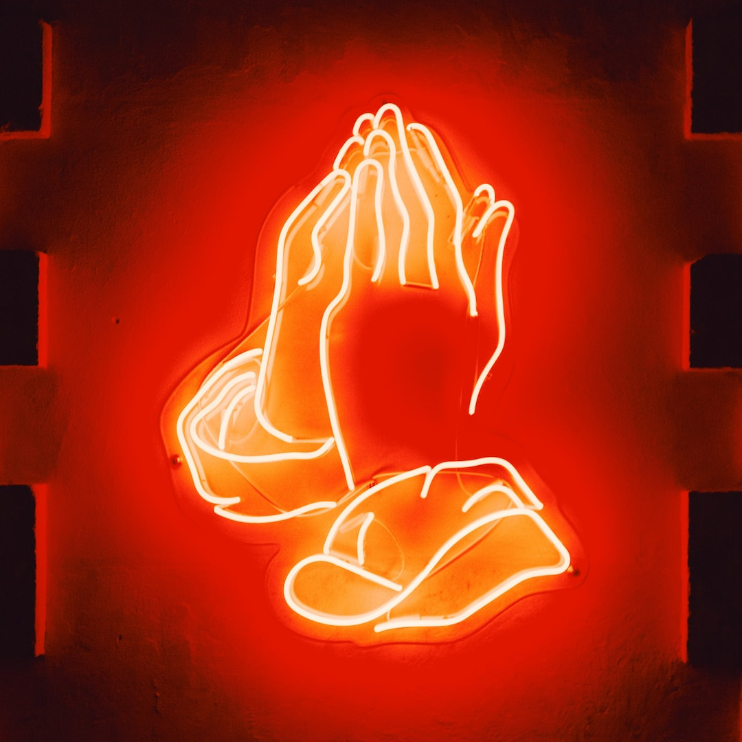 Czerwony neon w formie złożonych rąk do modlitwy