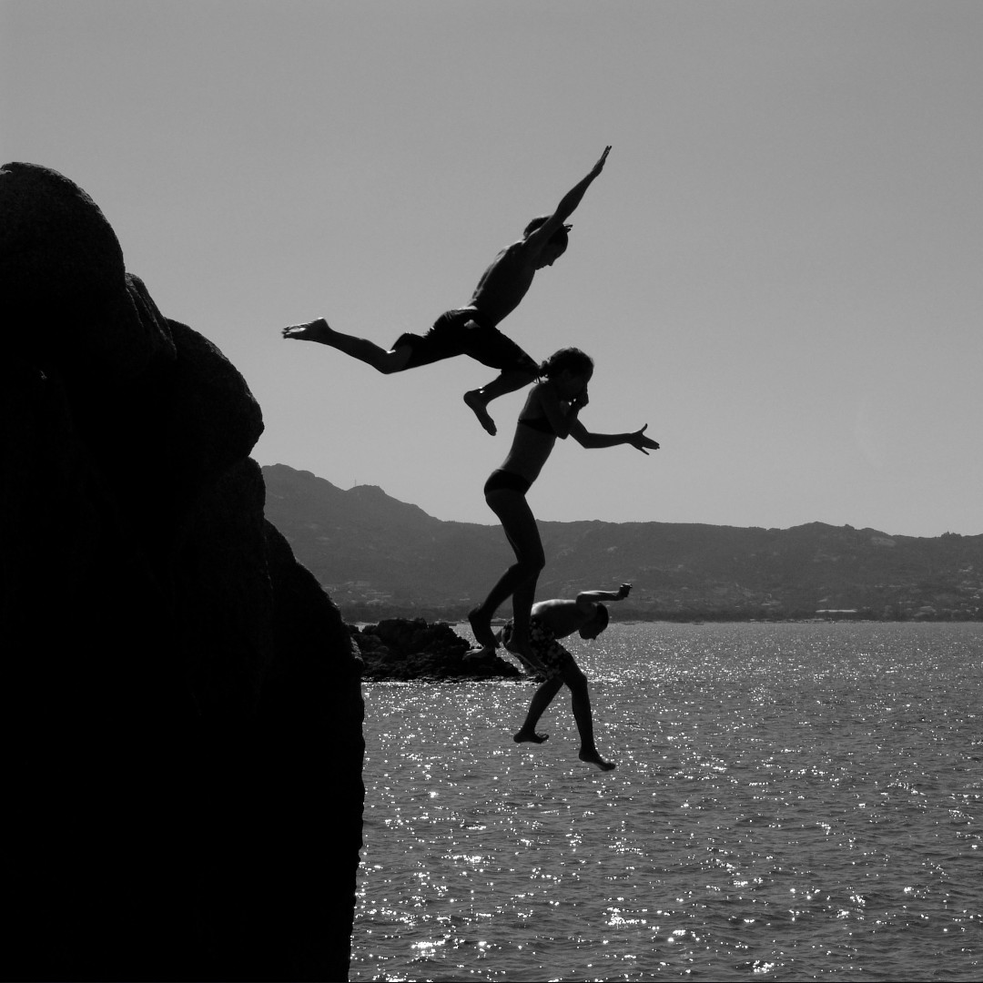 Mężczyźni skaczący ze skały do morza