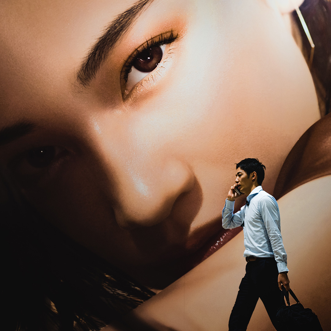 Idący człowiek na tle kobiecej twarzy na plakacie reklamowym