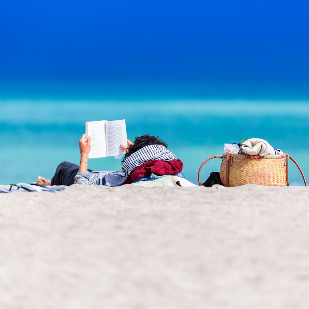 Kobieta czytająca książkę na plaży