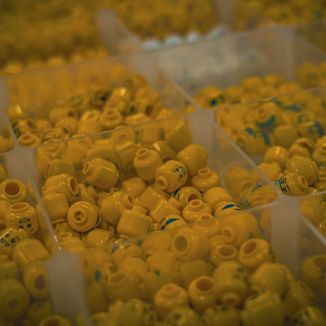 Plastikowe przegródki wypełnione główkami od ludzików LEGO